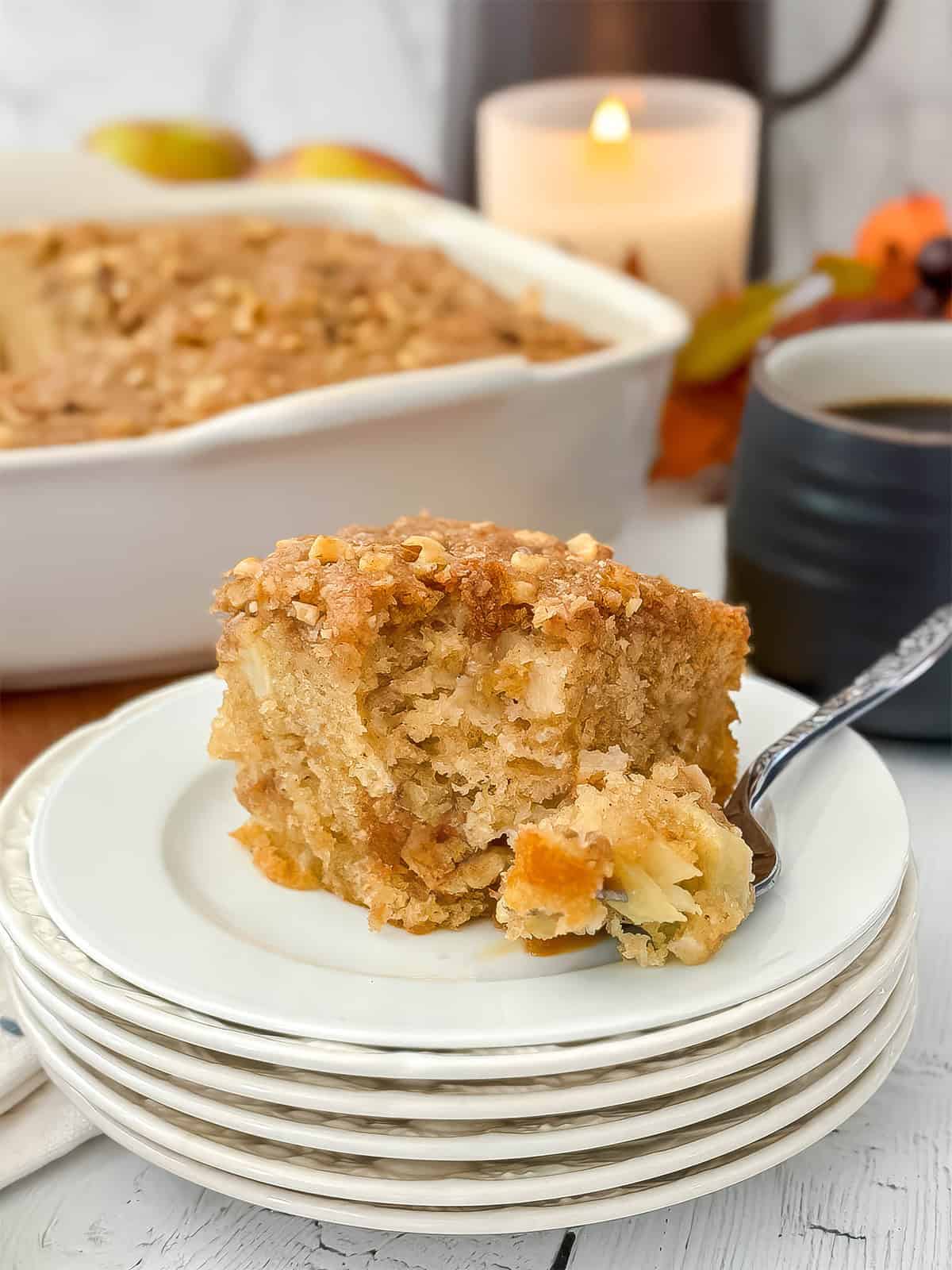 Serving of pecan streusel apple cake on a plate with a fork containing a bite of the cake.