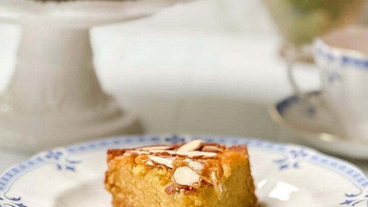 Side view of a slice of Honey Cake topped with sliced almonds on a blue and white plate.