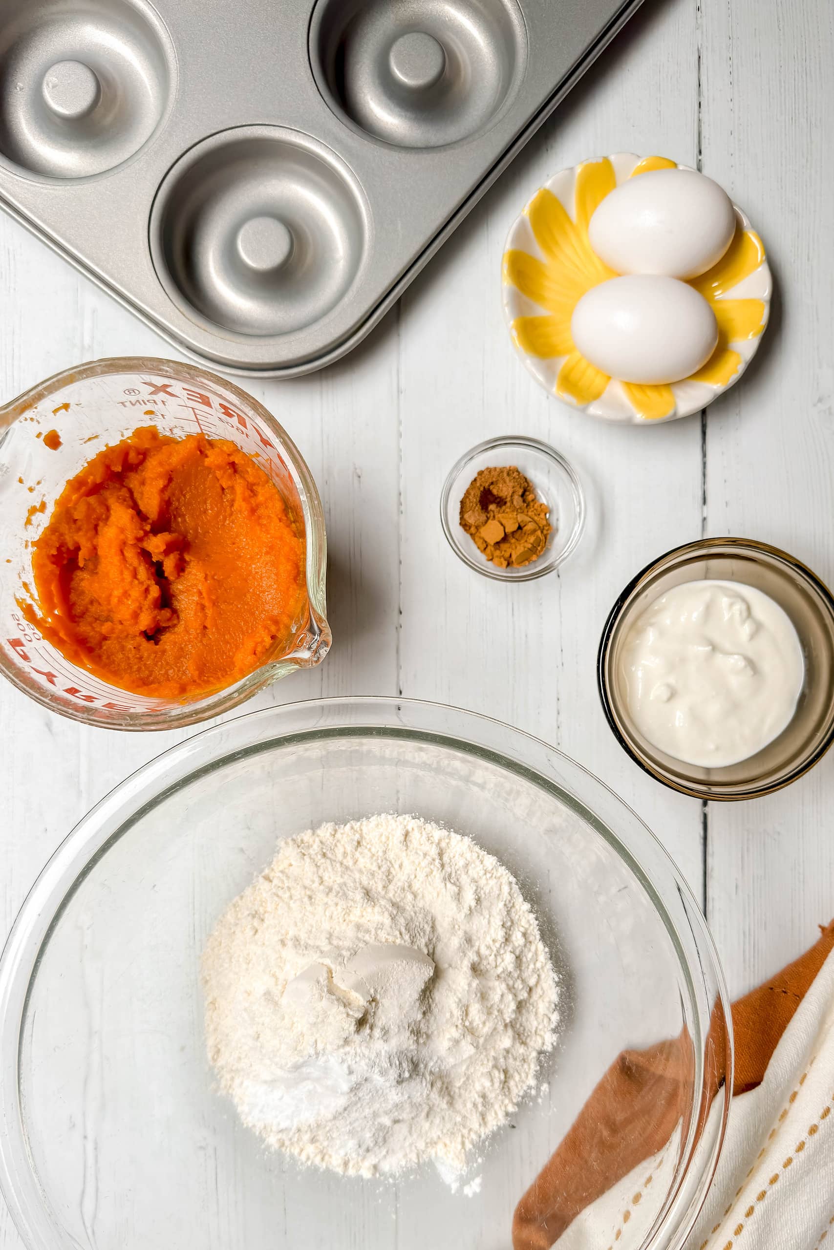 Top view of pumpkin donut ingredients on a white wood background