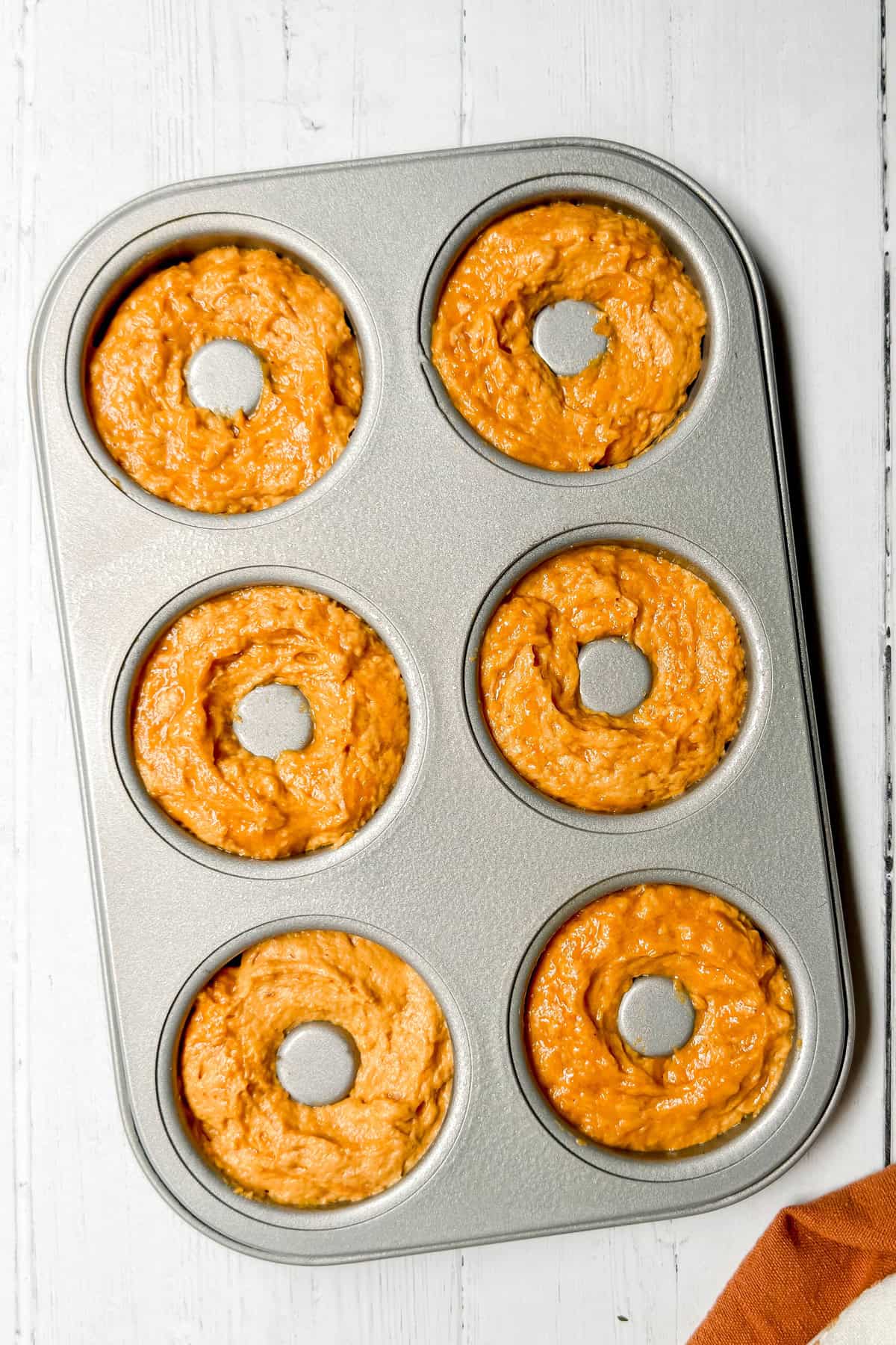 Unbaked pumpkin donut batter in a donut pan ready for baking.