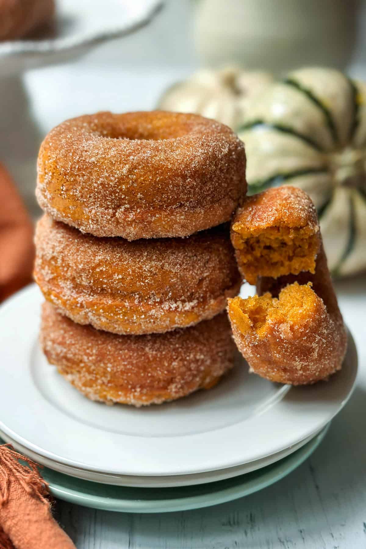 Stack of baked pumpkin donuts with cinnamon sugar coating on a plate 