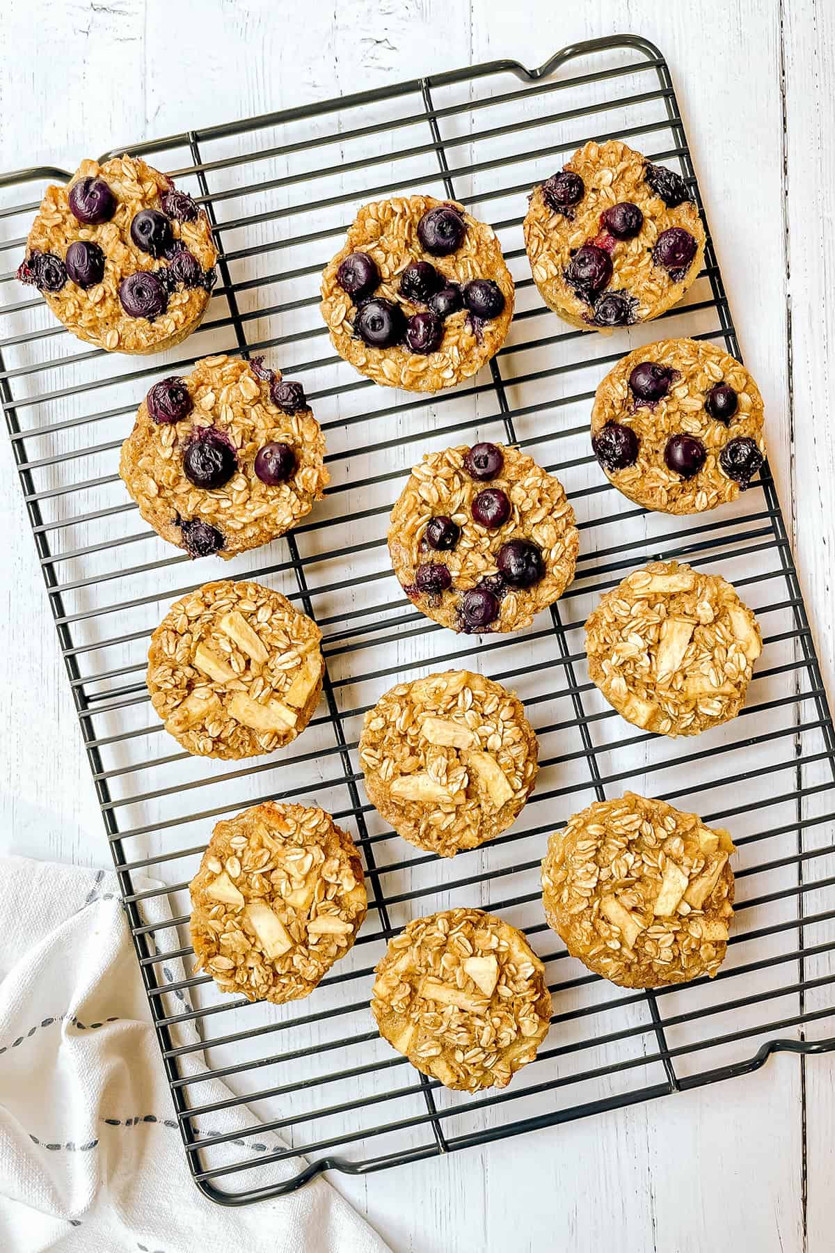 Freshly baked oatmeal cups with blueberries and apples cooling on a wire rack, golden and ready to serve.