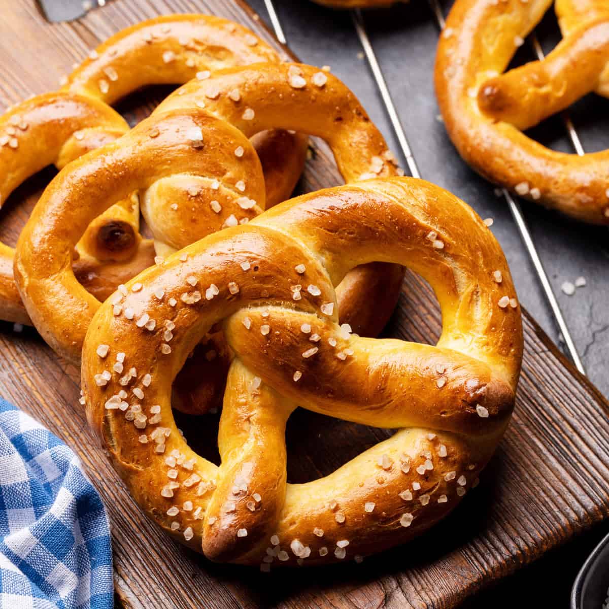 Fresh German Pretzels on a wooden table with a blue and white checked linen.