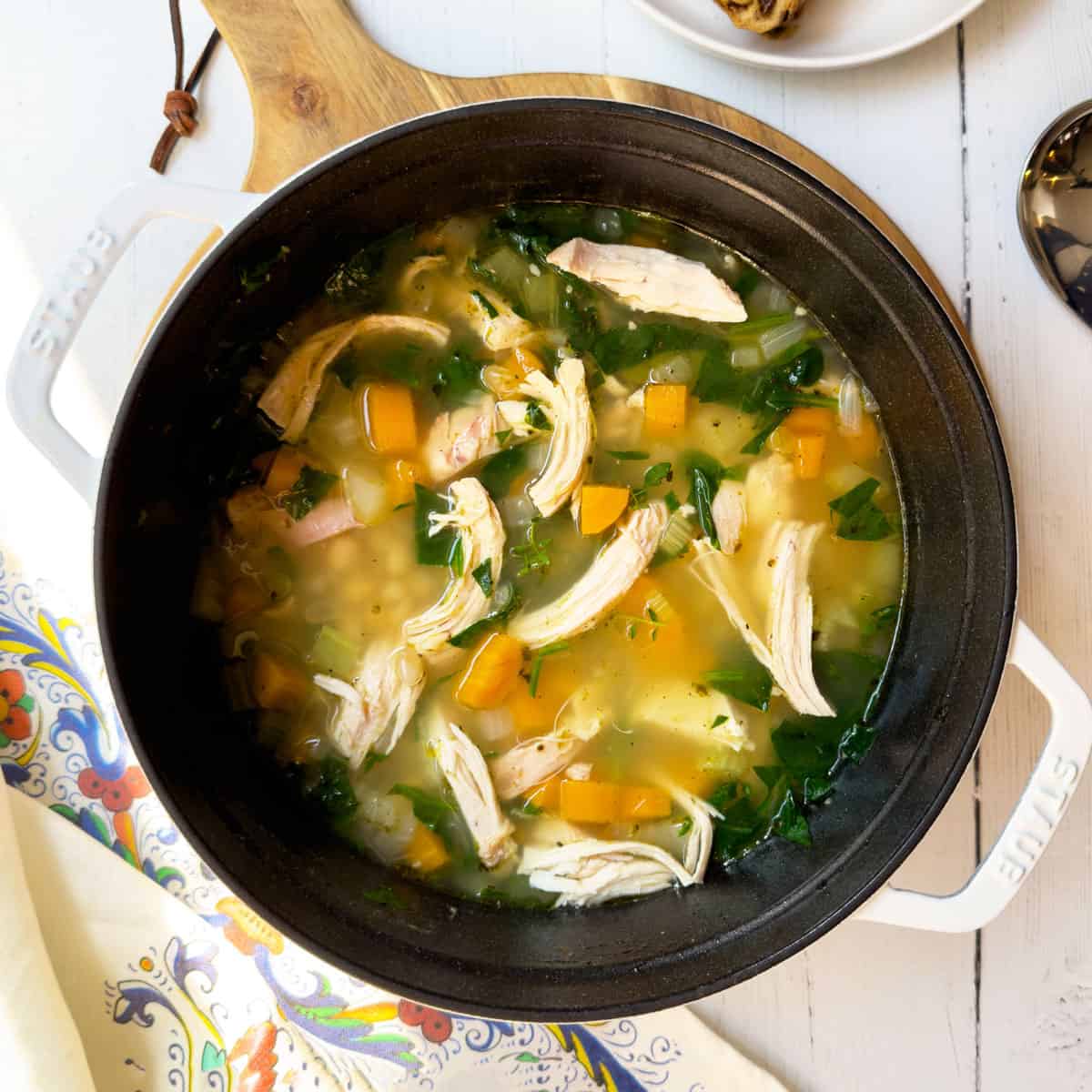 Adding cooked chicken, beans, and greens into a large pot and simmering.