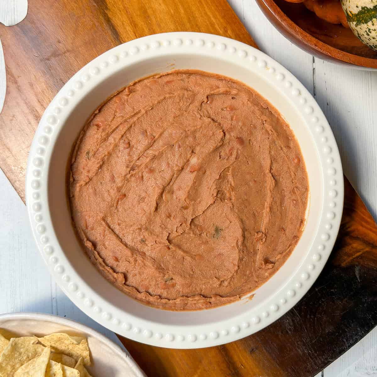 Serving dish filled with refried beans as the first layer in Halloween 7 Layer Dip.