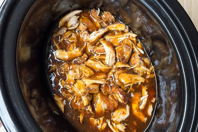 Top view of crockpot honey garlic chicken in a black slow cooker