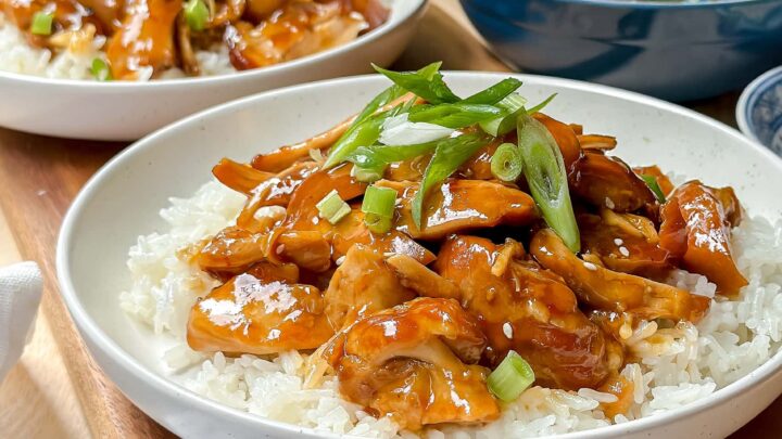 Closeup side view of Slow Cooker Honey Garlic Chicken over rice with spinach in the background