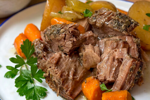 Closeup view of plated Slow Cooker Pot Roast with carrots, onions, and potatoes.