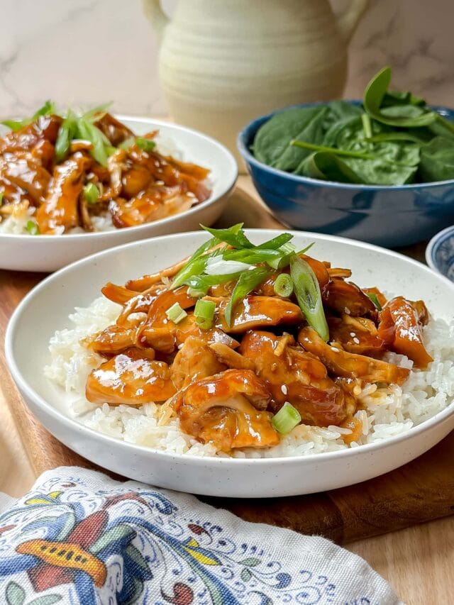 Closeup side view of Slow Cooker Honey Garlic Chicken over rice with spinach in the background