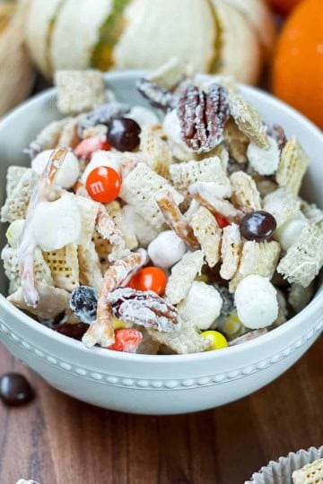Fall snack mix with Chex cereal, autumn candies, pretzels and white chocolate in a bowl on a Harvest table.