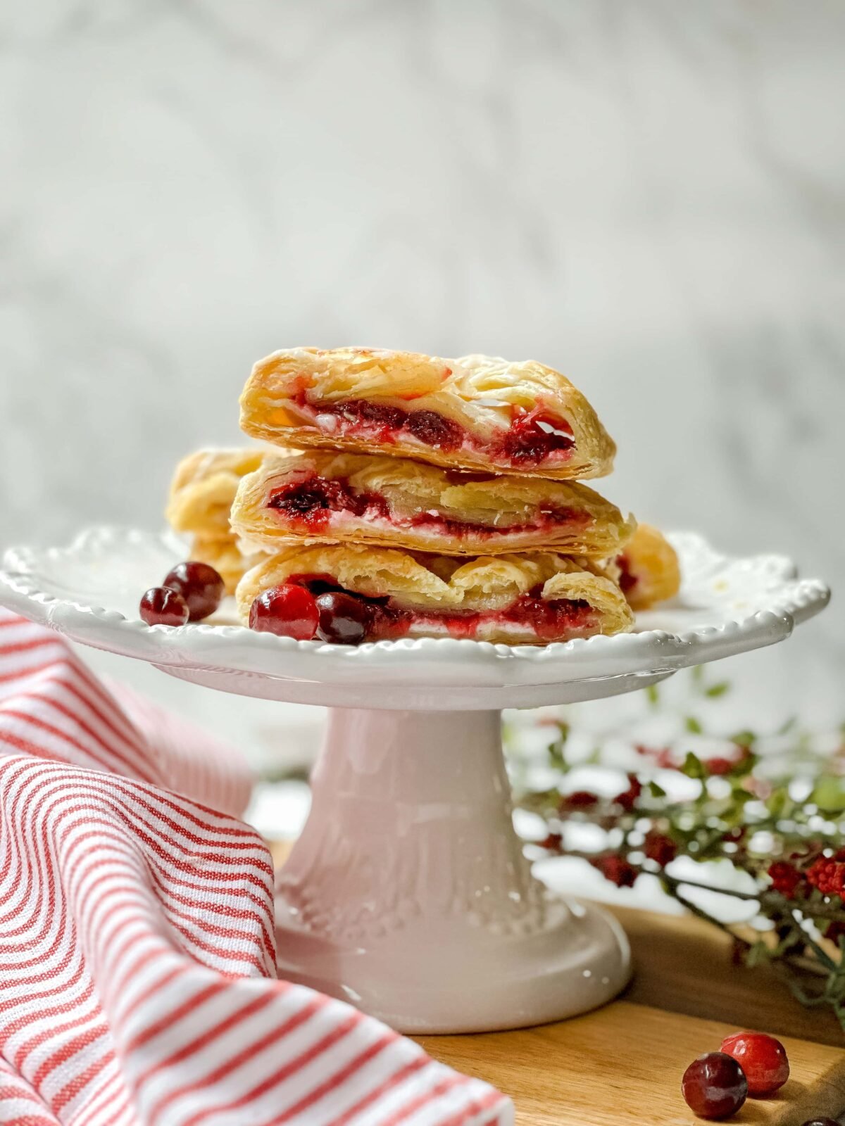 Slices of Cranberry Cream Cheese Danish stacked on a white scalloped cake stand