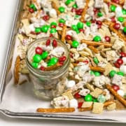 Christmas Crack Snack Mix on a parchment lined baking sheet with a glass jar for gifting.