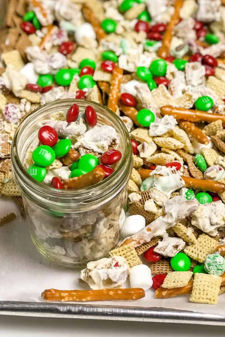 Christmas Crack Snack Mix on a parchment lined baking sheet with a glass jar for gifting.