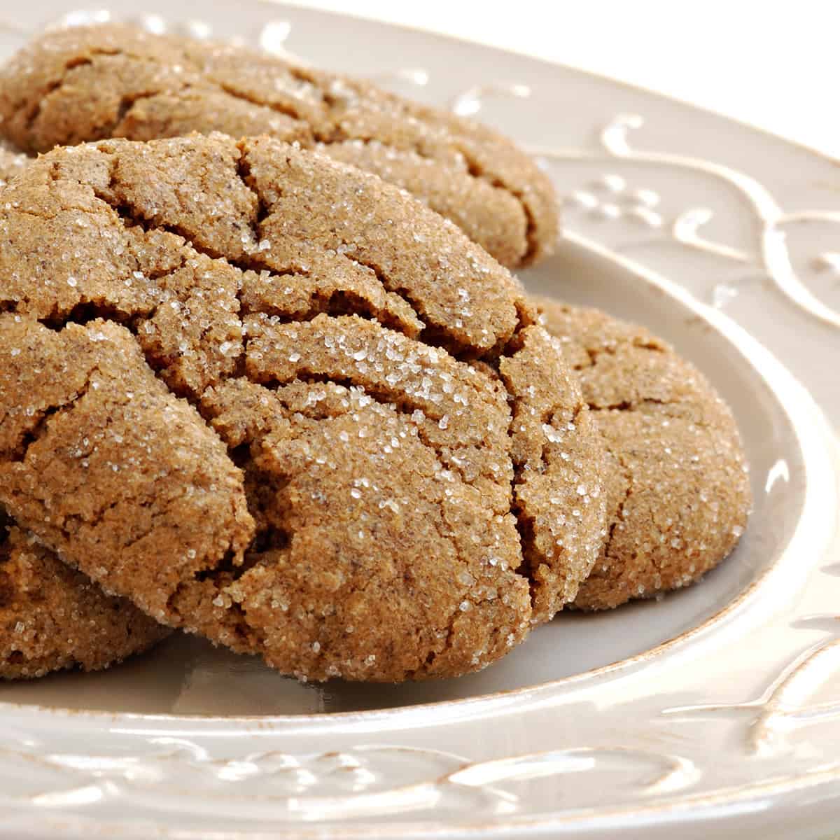 Square image of stacked ginger spice cookies on a white plate ready for serving.