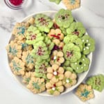 Square image of colorful spritz cookies on a large plate and decorated with sprinkles.