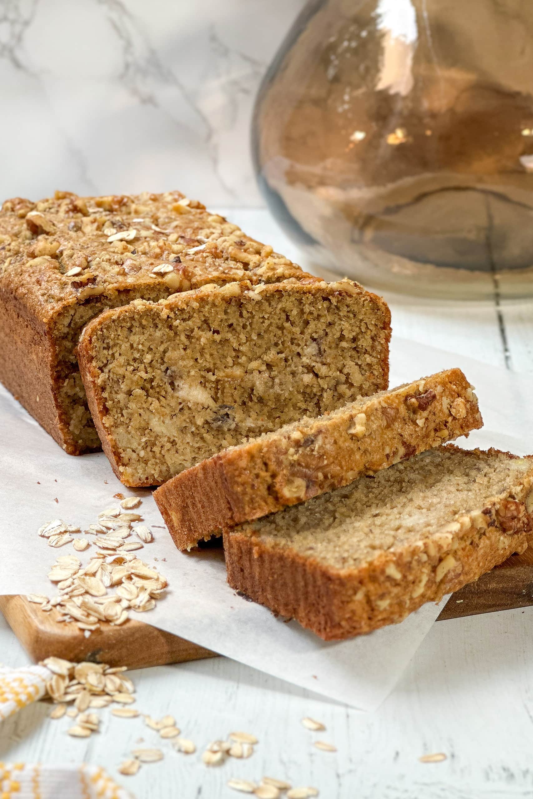 Side view of sliced Oat Flour Banana Bread on a wood cutting board.