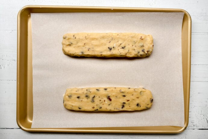 Top horizontal view of unbaked biscotti logs on a parchment lined baking sheet.