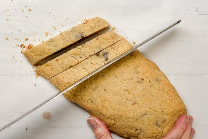 Top horizontal view of biscotti log cut into slices using a serrated knife.
