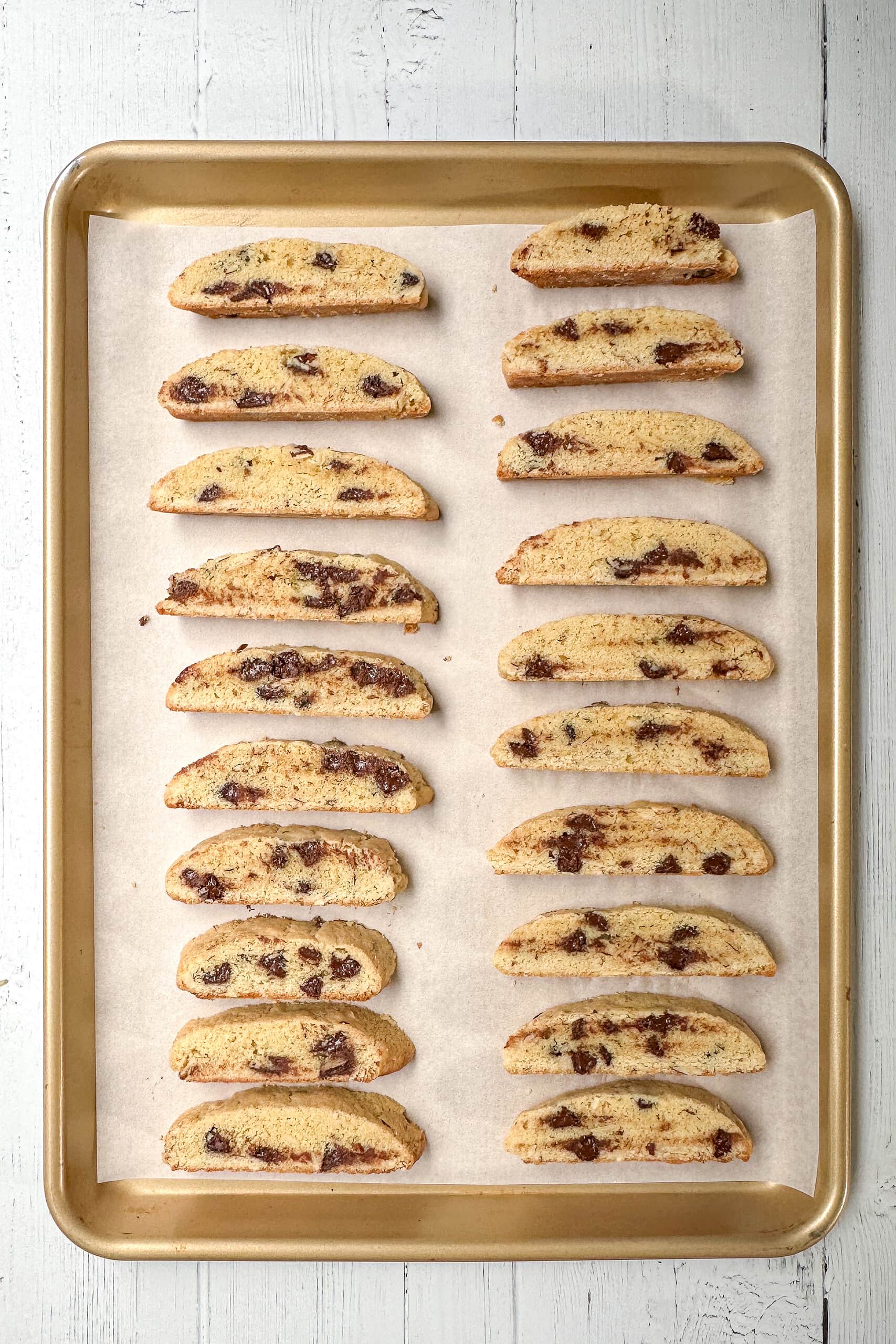 Top view of biscotti slices on a parchment lined baking sheet ready for second baking.
