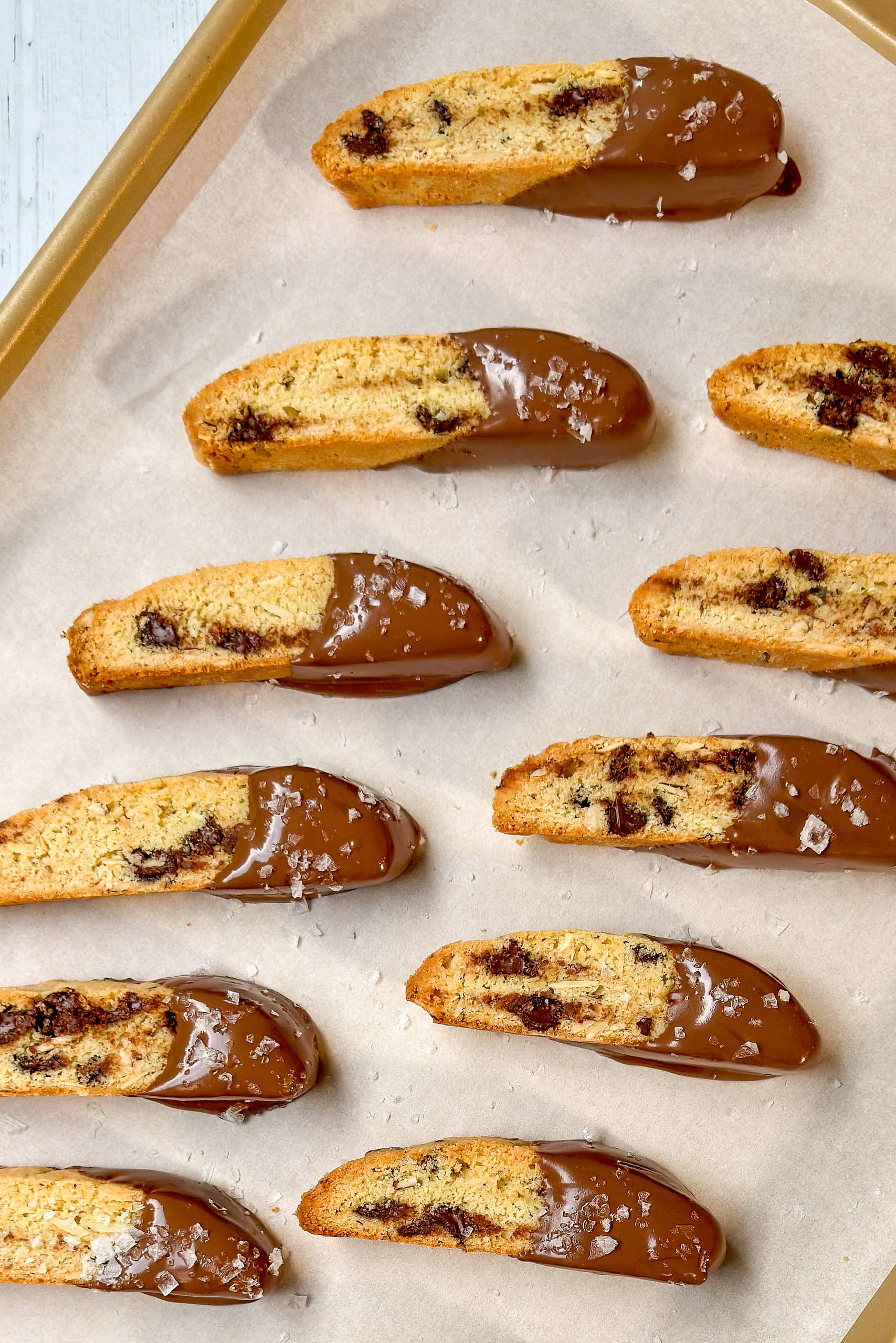 Top view of chocolate dipped biscotti on a parchment lined baking tray.