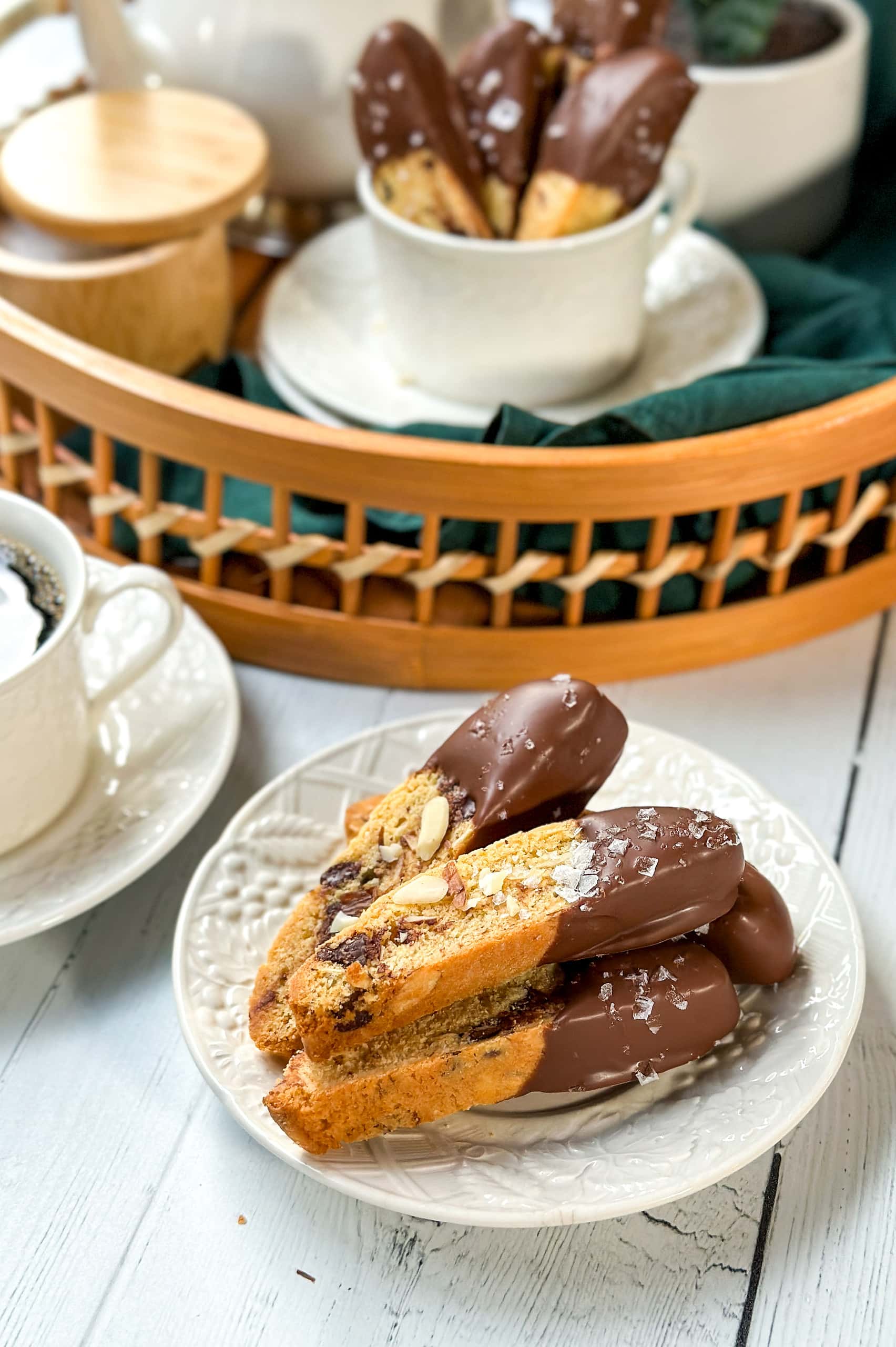 Side view of Chocolate Almond Biscotti on a white plate with a coffee station in the backgrouond.