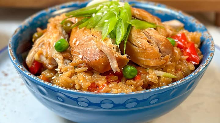 Side view of Instant Pot Teriyaki Chicken and Rice in a blue bowl with chopped green onions and sesame seeds.