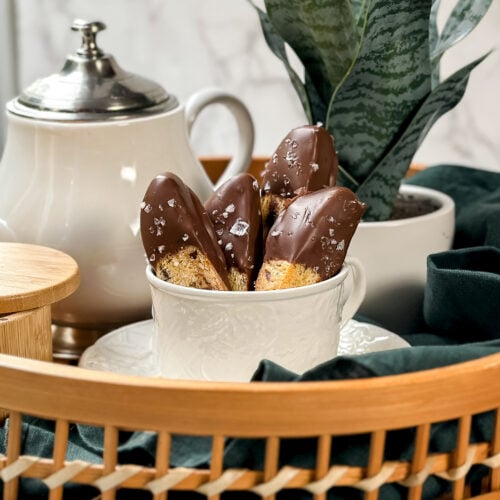 Closeup side view of Italian Chocolate Almond Biscotti in a woven tray with coffee and tea.