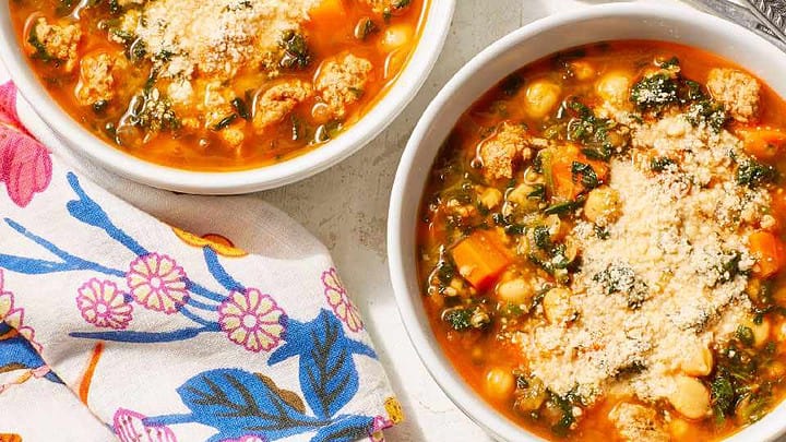 Top distant view of two white bowls of chickpea and spinach stew with parmesan cheese.