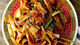 Top view of yakisoba with pork and cabbage in a steel wok