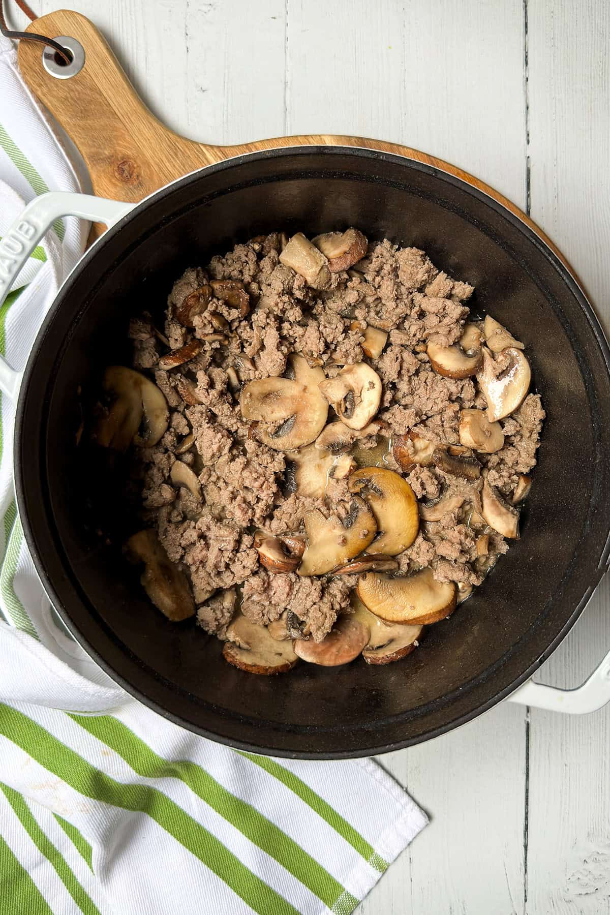 A black pot containing saut&eacute;ing ground turkey and sliced mushrooms, perfect for pairing with your asparagus pasta.