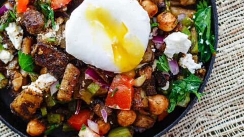 Top view of Medigterranean Potato Hash with asparagus, chickpeas, and poached eggs on top in a black cast iron skillet.