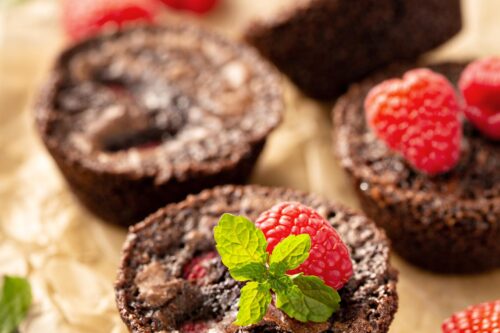 Horizontal side view of brownie bites with mint and fresh raspberries.