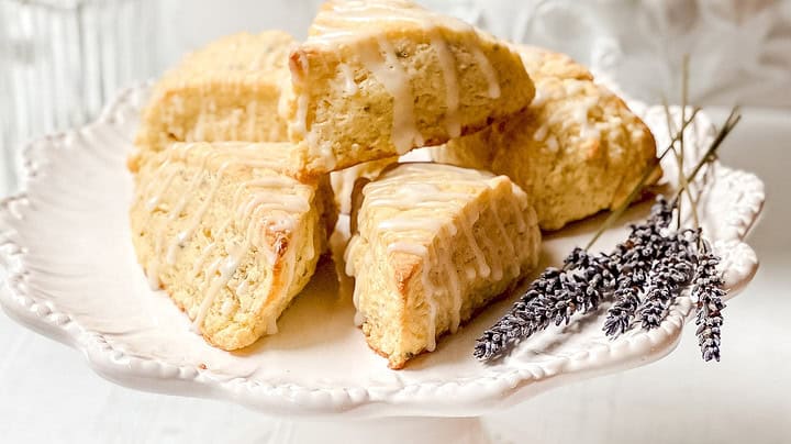 Side view of stacked lemon scones on a white dessert stand with a white teapot in the background.