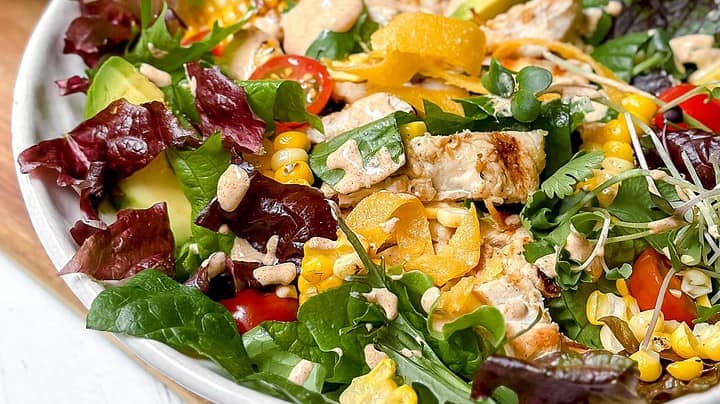Closeup view of grilled chicken salad with creamy and healthy Southwest Salad Dressing in a white bowl.
