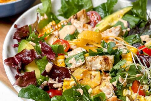Closeup view of grilled chicken salad with creamy and healthy Southwest Salad Dressing in a white bowl.