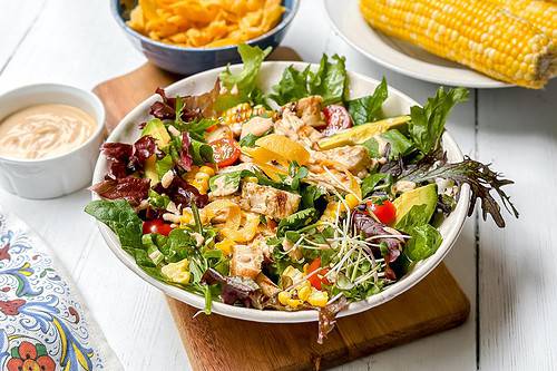 Horizontal top view of Southwest Chicken Salad with crispy strips and grilled corn.