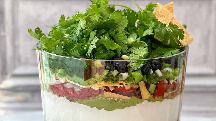 Side view of 7 Layer Dip in a glass trifle dish.
