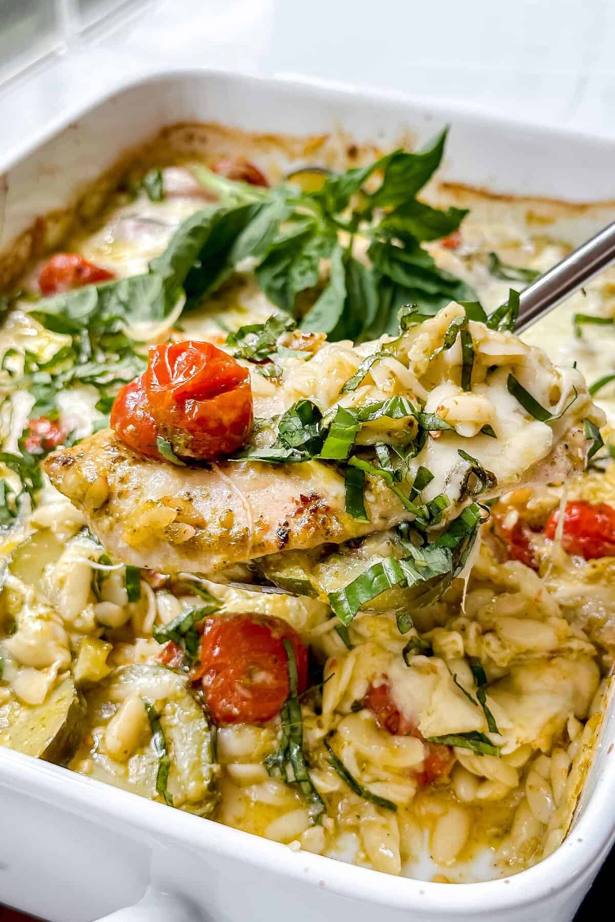 Closeup view of baked Caprese Pesto Chicken on a silver spoon.