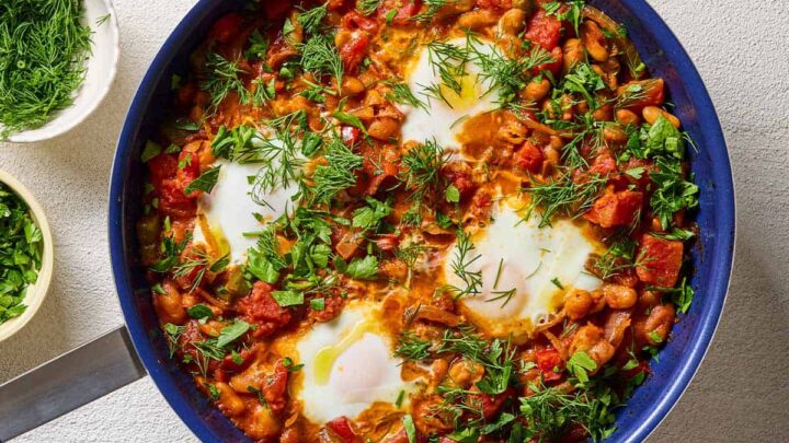 Top view of White Bean Shakshuka in a blue skillet with fresh dill.