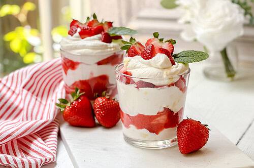 Horizontal view of 2 Eton Mess no bake desserts on a white marble board.