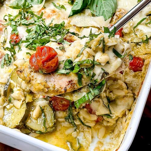 Horizontal closeup view of pesto chicken serving from white casserole dish.