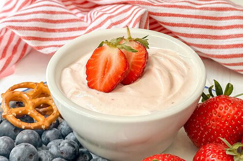 Horizontal side view of strawberry yogurt dip with sliced strawberries on top.