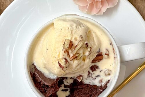 Top view of brownie mug cake in a white mug with vanilla ice cream.