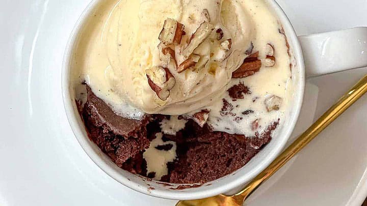 Top view of brownie mug cake in a white mug with vanilla ice cream.