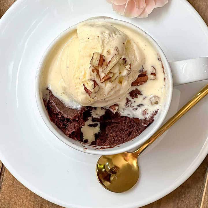 Top view of brownie mug cake in a white mug with vanilla ice cream.