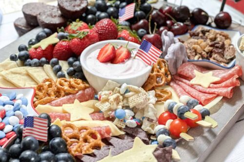 Close up horizontal view of 4th of July Snack Board with Strawberry Yogurt Dip, fruit, vegetables and treats.