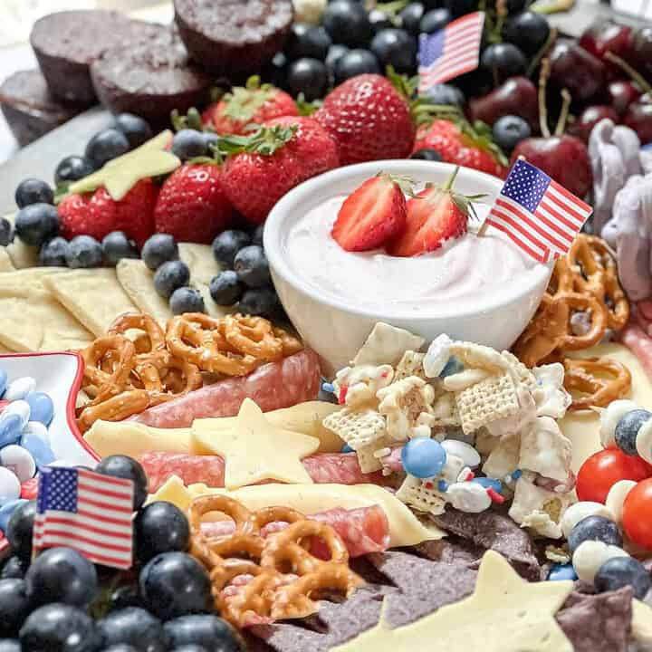 Close up horizontal view of 4th of July Snack Board with Strawberry Yogurt Dip, fruit, vegetables and treats.