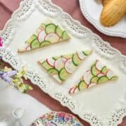 Top view of cucumber an radish tea sandwiches on a rectangular tea serving platter.