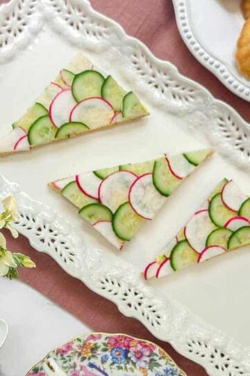 Top view of cucumber an radish tea sandwiches on a rectangular tea serving platter.