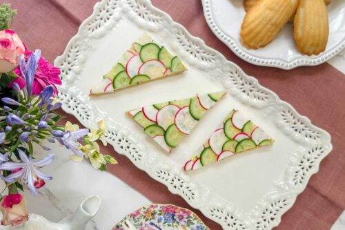 Top view of cucumber an radish tea sandwiches on a rectangular tea serving platter.